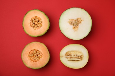 Cut different types of melons on red background, flat lay