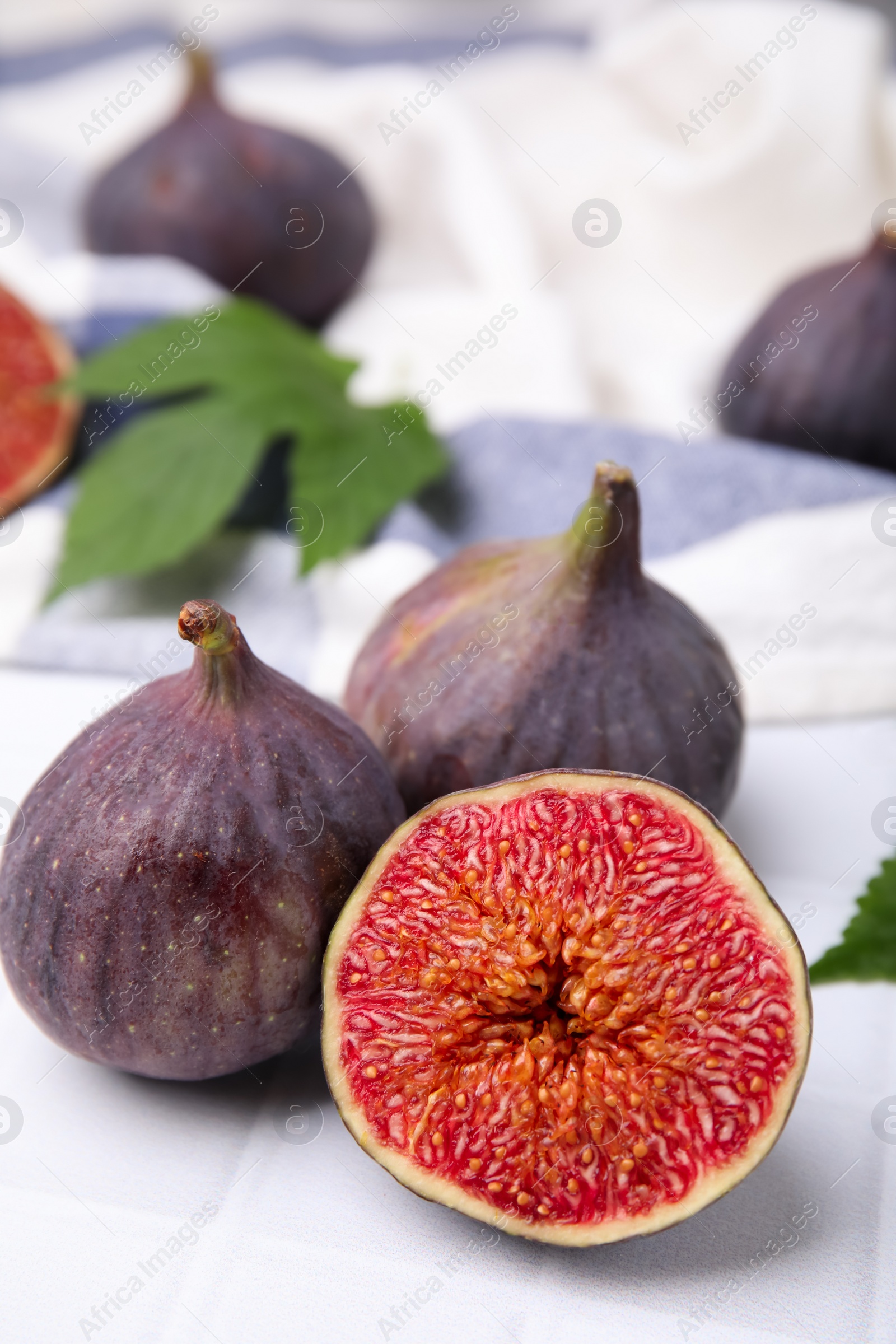 Photo of Fresh ripe purple figs on white tiled table, closeup