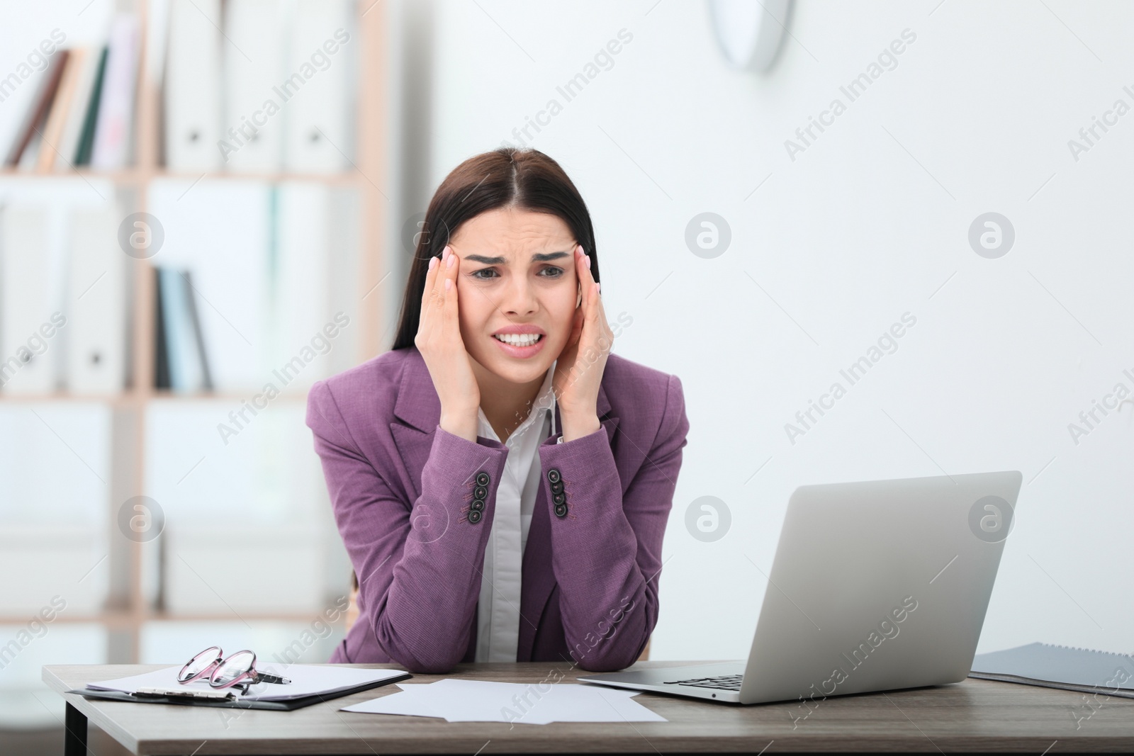 Photo of Woman suffering from migraine at workplace in office