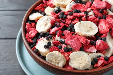 Photo of Bowl of different freeze dried fruits on wooden table, closeup