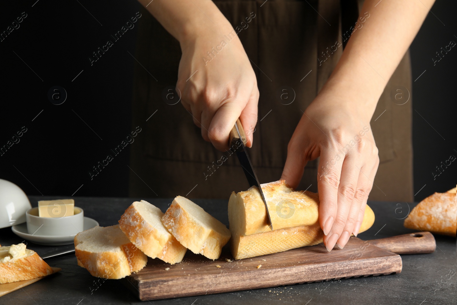 Photo of Woman cutting bread on wooden board, closeup