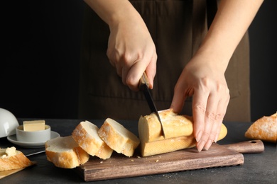 Photo of Woman cutting bread on wooden board, closeup