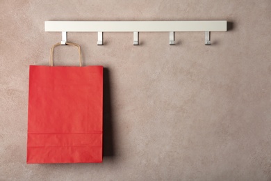 Photo of Rack with paper shopping bag on color wall