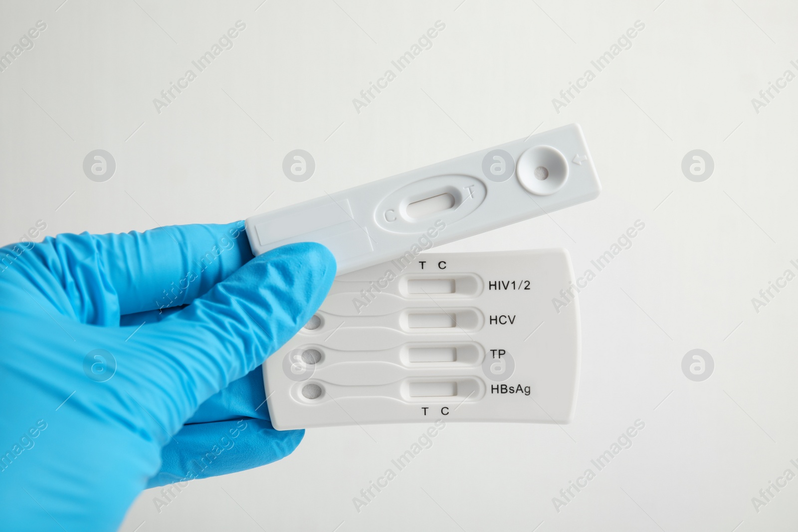 Photo of Doctor holding two disposable express tests for hepatitis on white background, closeup