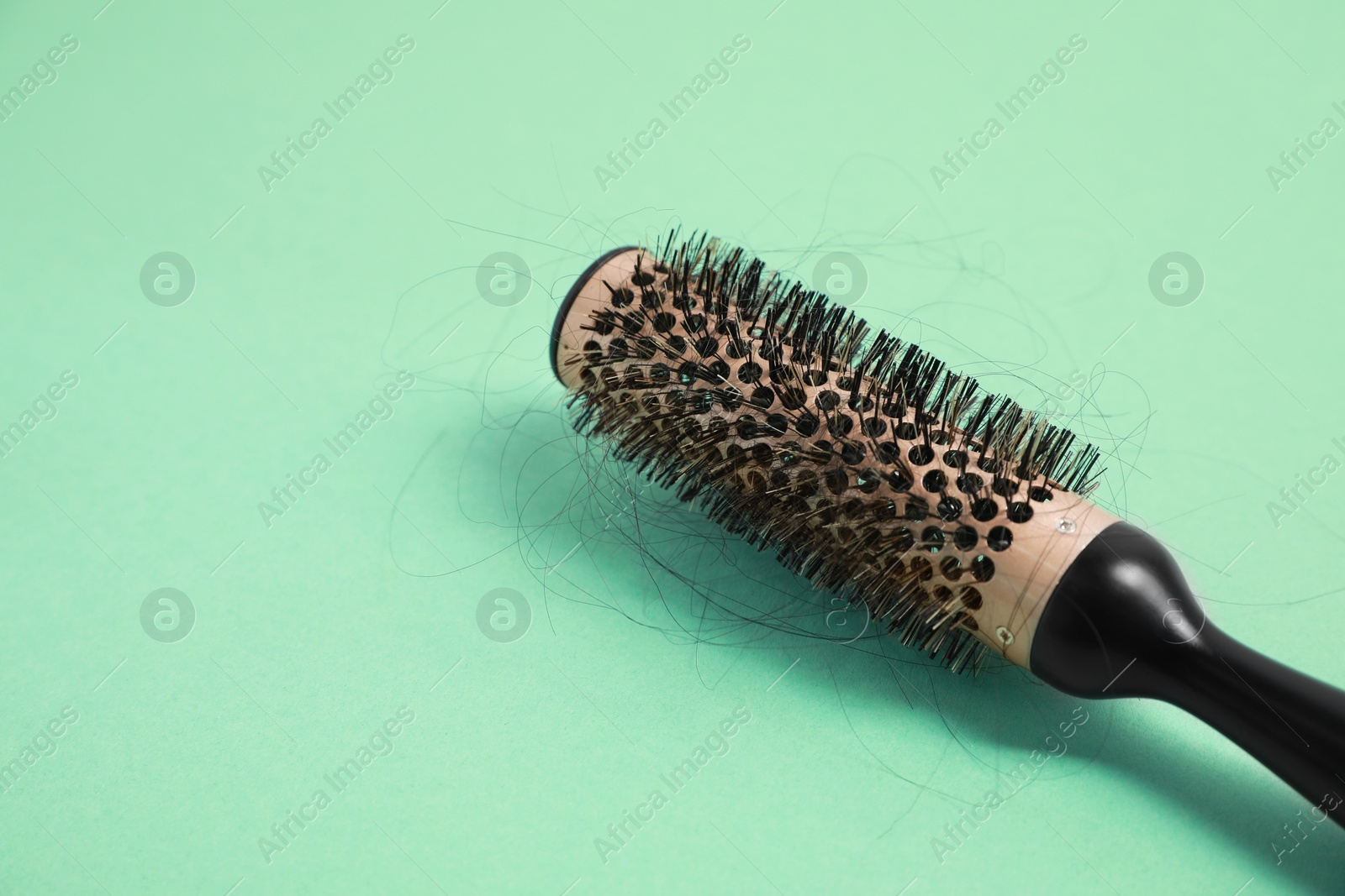 Photo of Professional brush with lost hair on green background, closeup. Space for text