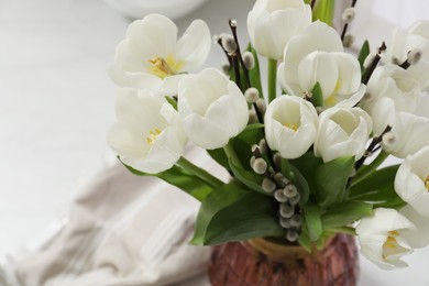Photo of Beautiful bouquet of willow branches and tulips in vase on white table, above view