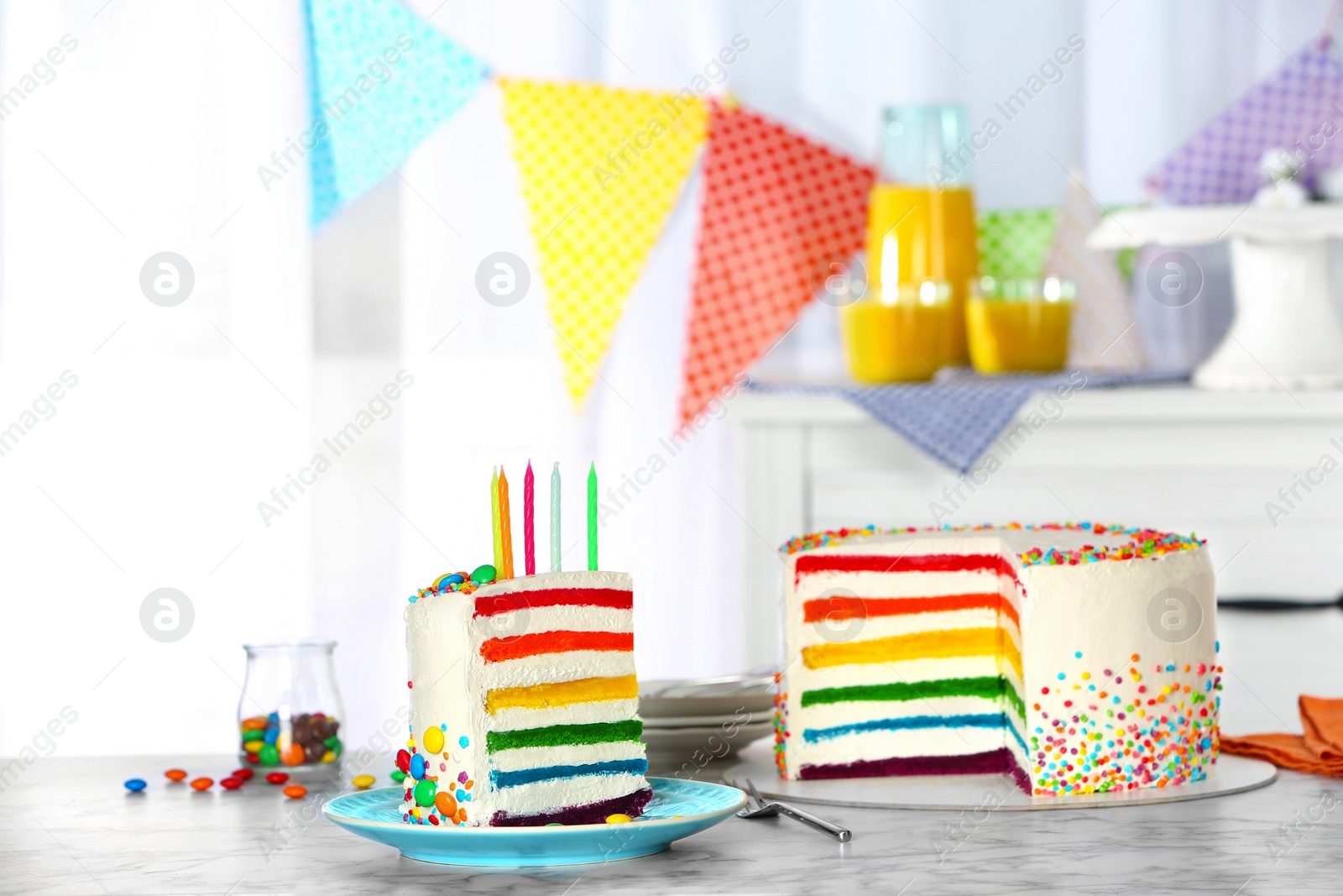 Photo of Delicious rainbow cake with candles for party on table