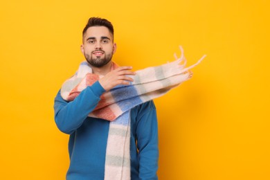 Photo of Smiling man in warm scarf on yellow background. Space for text