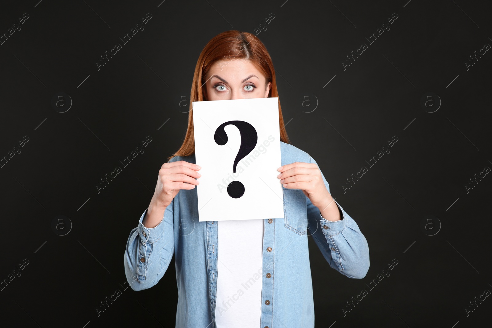 Photo of Woman holding question mark sign on black background