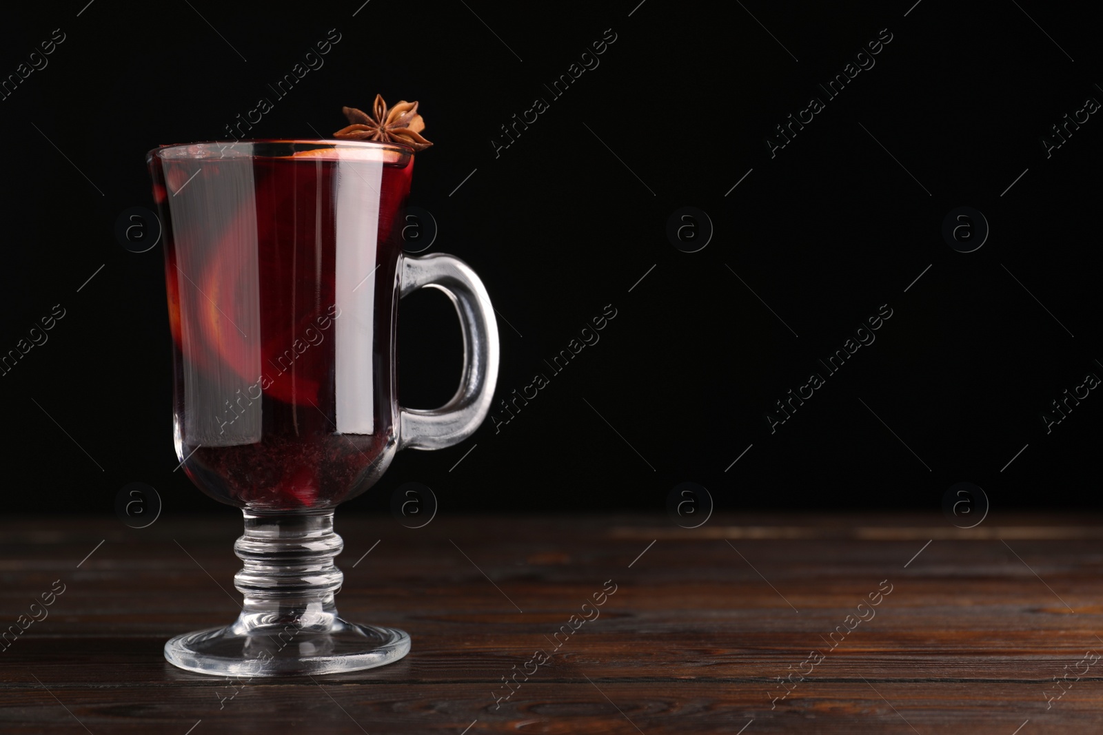 Photo of Aromatic mulled wine on wooden table. Space for text