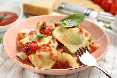 Photo of Tasty ravioli with tomato sauce served on table, closeup