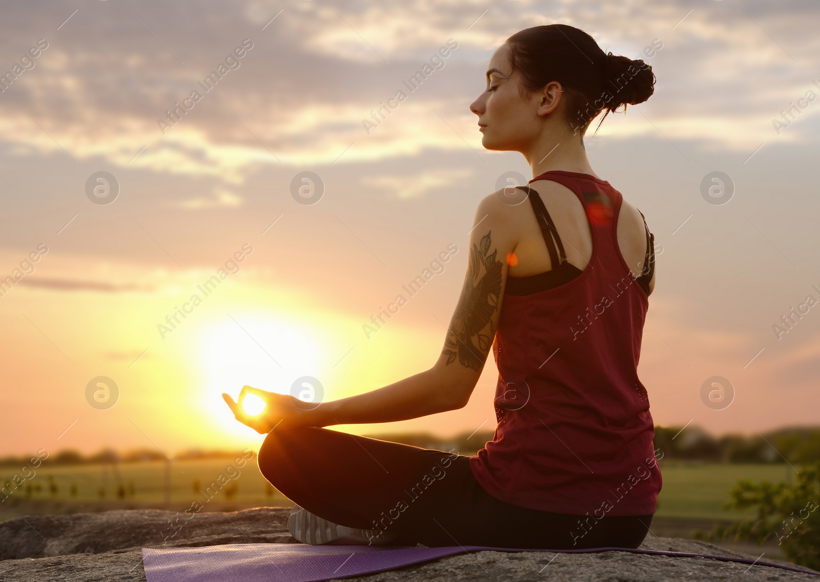 Photo of Young woman practicing zen yoga at sunrise outdoors