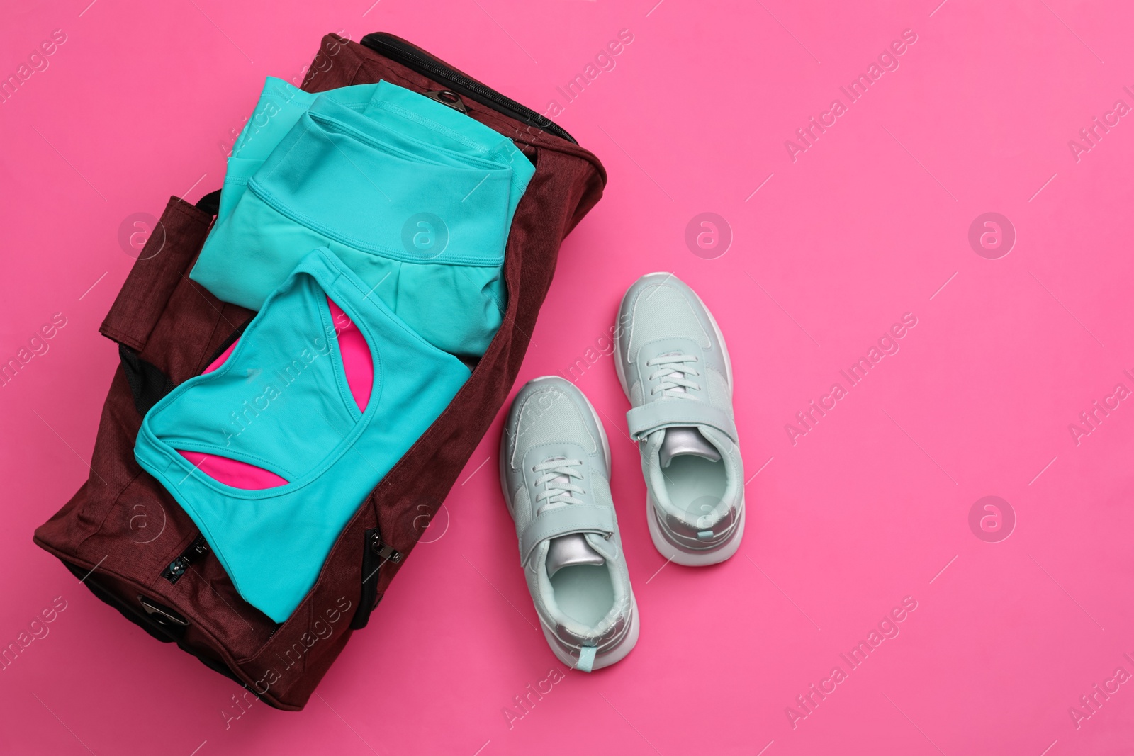 Photo of Gym bag and sports equipment on pink background, flat lay. Space for text