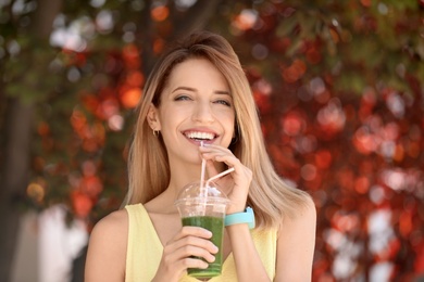 Photo of Young woman with plastic cup of healthy smoothie outdoors