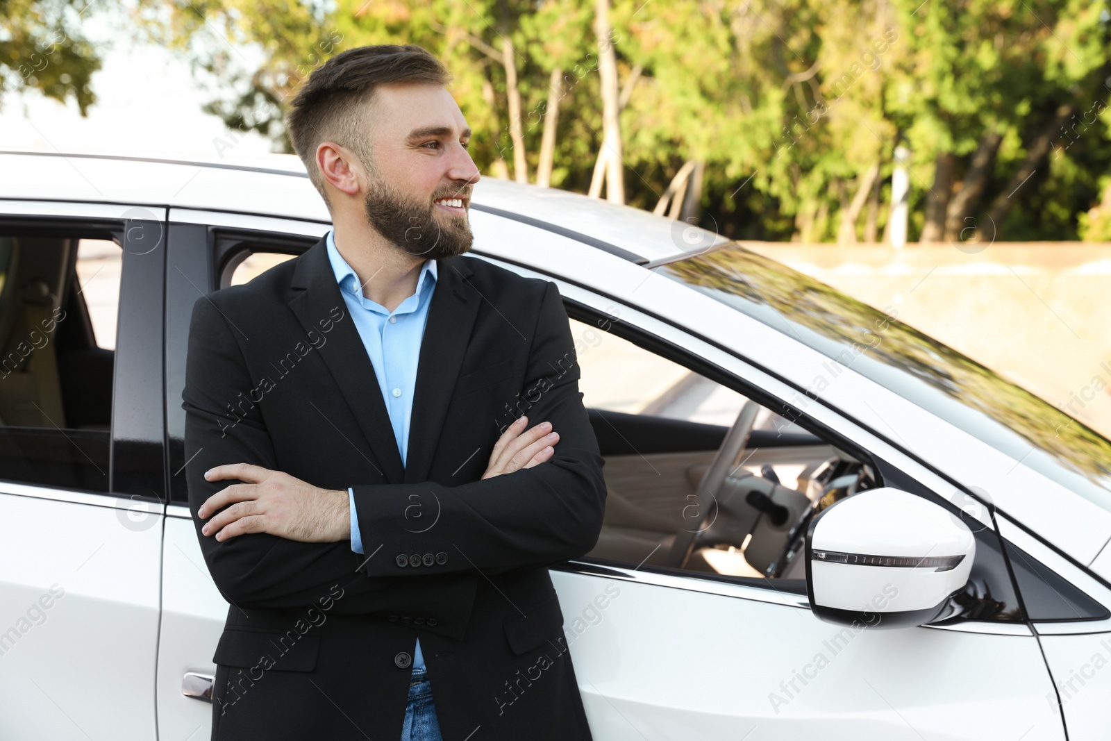 Photo of Handsome young driver near modern car on city street