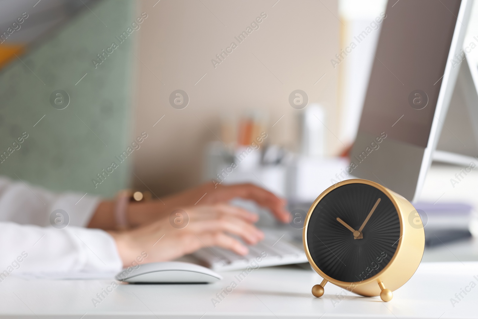 Photo of Alarm clock and blurred woman working on background. Time management