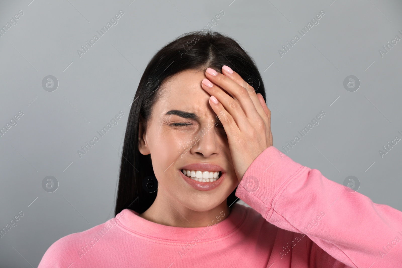 Photo of Woman suffering from migraine on grey background