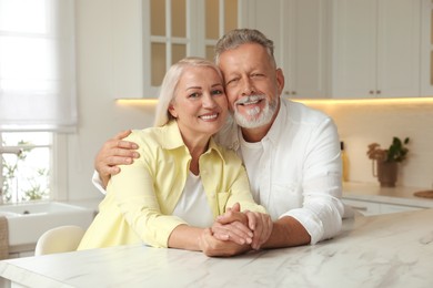 Photo of Happy senior couple at table in kitchen