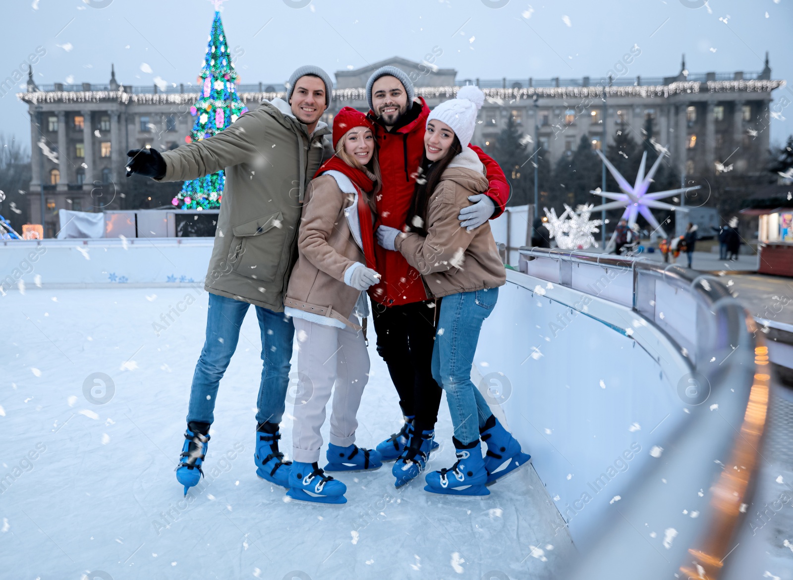 Image of Group of friends near fence at outdoor ice rink