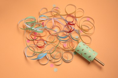 Photo of Beautiful serpentine and confetti bursting out of party popper on coral background