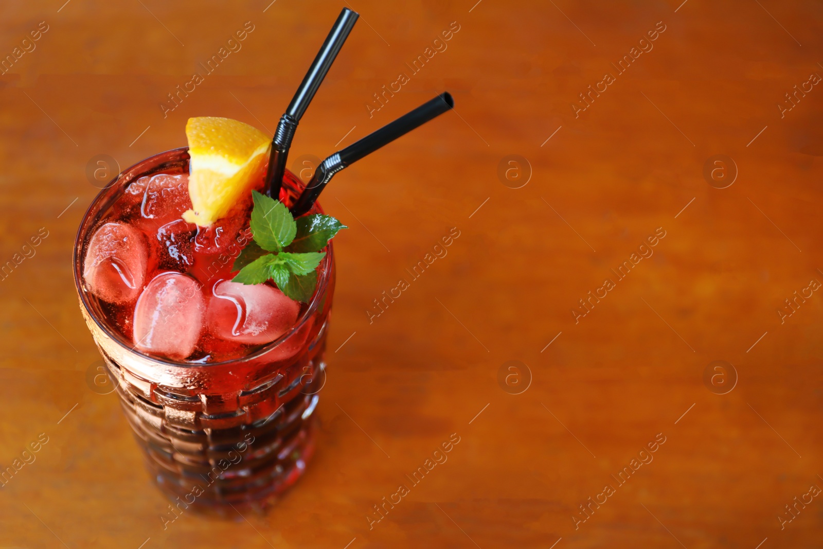 Photo of Glass of delicious cocktail with ice on table in bar