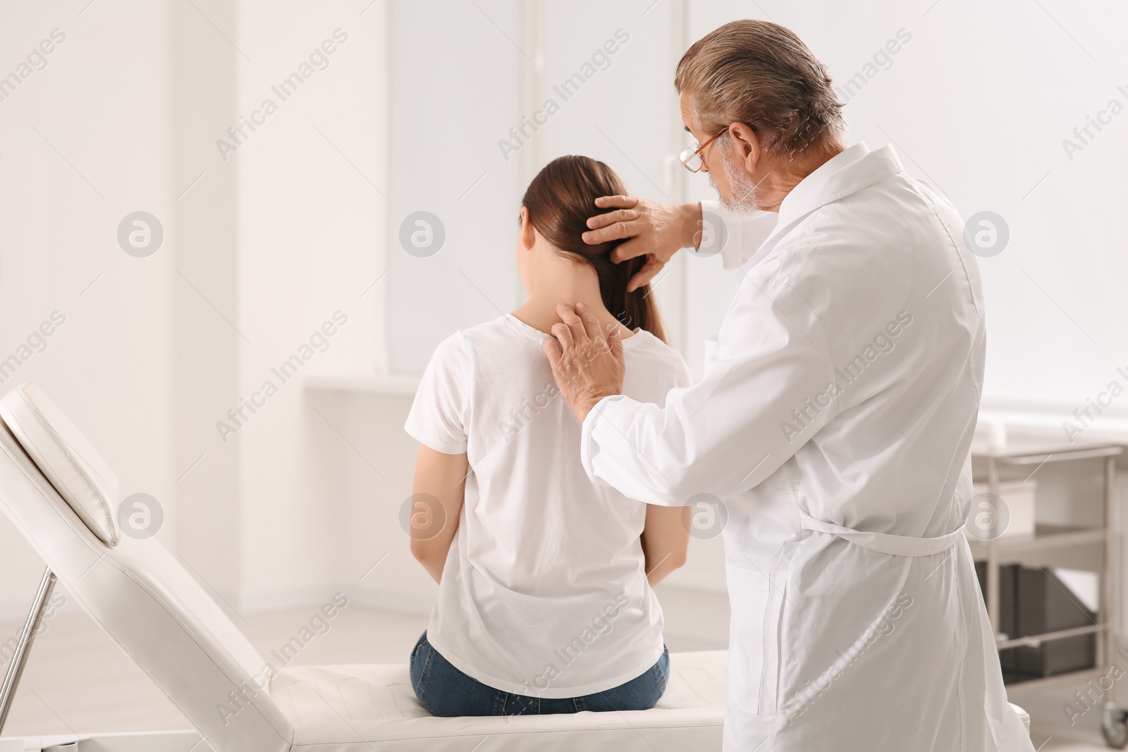 Photo of Professional orthopedist examining patient's neck in clinic