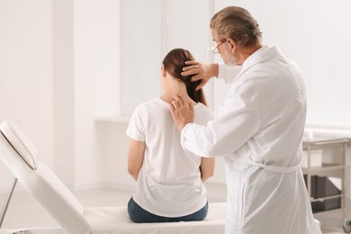 Photo of Professional orthopedist examining patient's neck in clinic