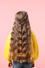 Photo of Little girl with braided hair on pink background, back view