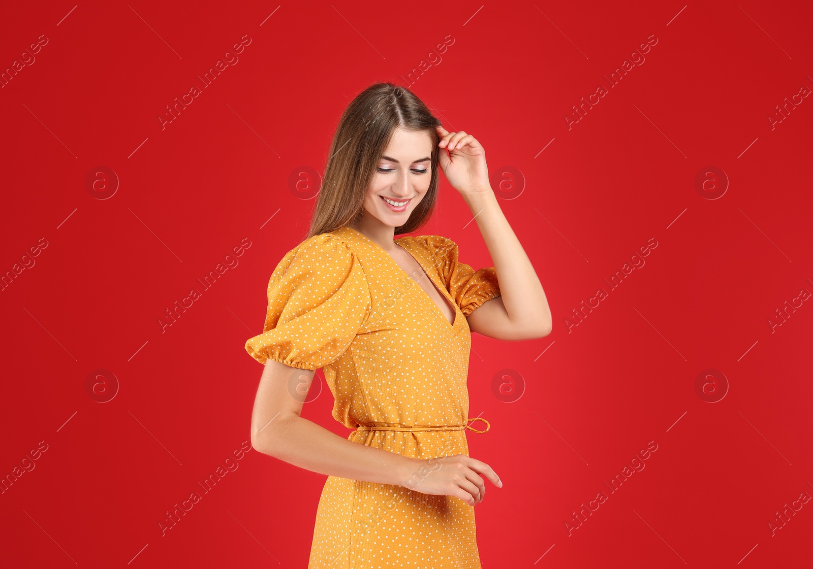 Photo of Young woman wearing stylish yellow dress on red background