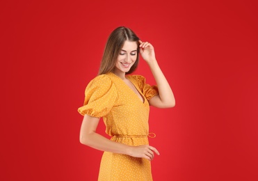 Young woman wearing stylish yellow dress on red background