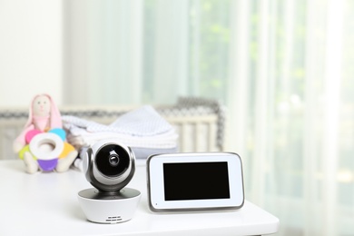 Photo of Baby monitor with camera and accessories on table in room. Video nanny
