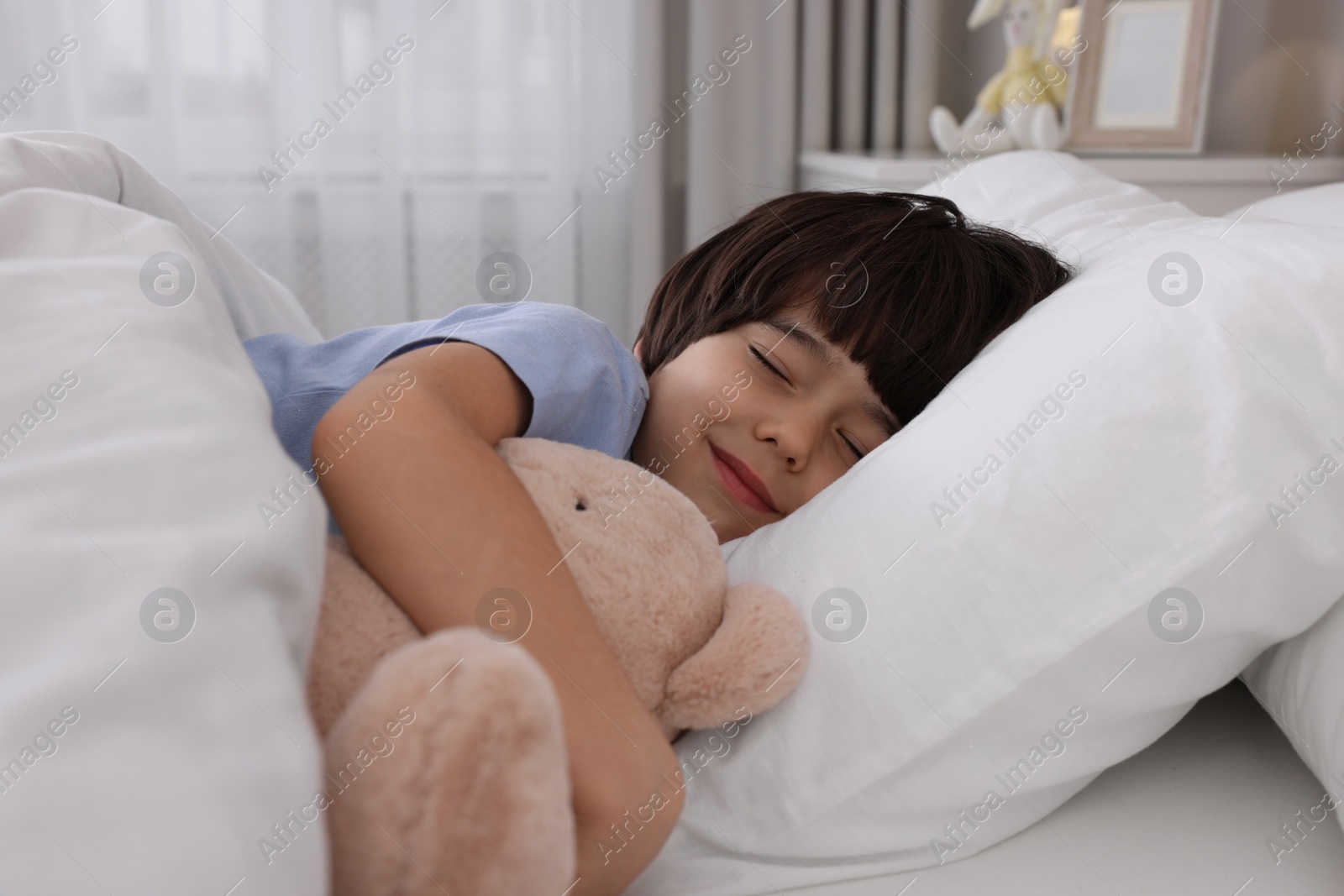 Photo of Cute little boy with toy bear sleeping in bed at home