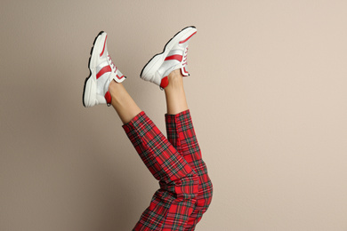 Photo of Woman wearing sneakers on beige background, closeup