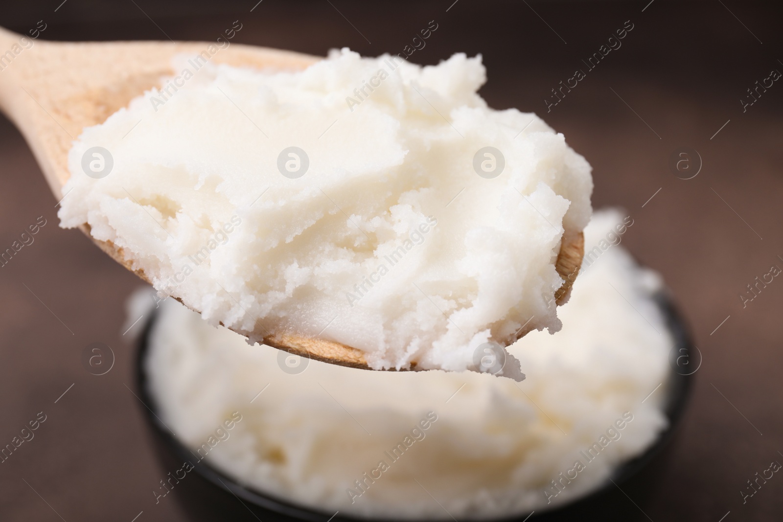 Photo of Wooden spoon with delicious pork lard on brown background, closeup