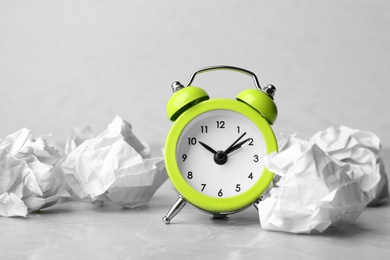 Photo of Crumpled paper balls and alarm clock on grey table