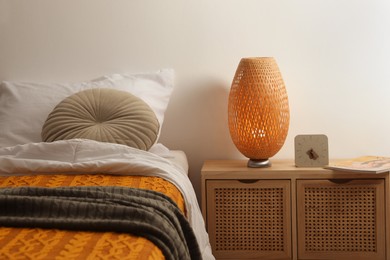 Photo of Stylish lamp, magazine and alarm clock on bedside table indoors. Bedroom interior elements