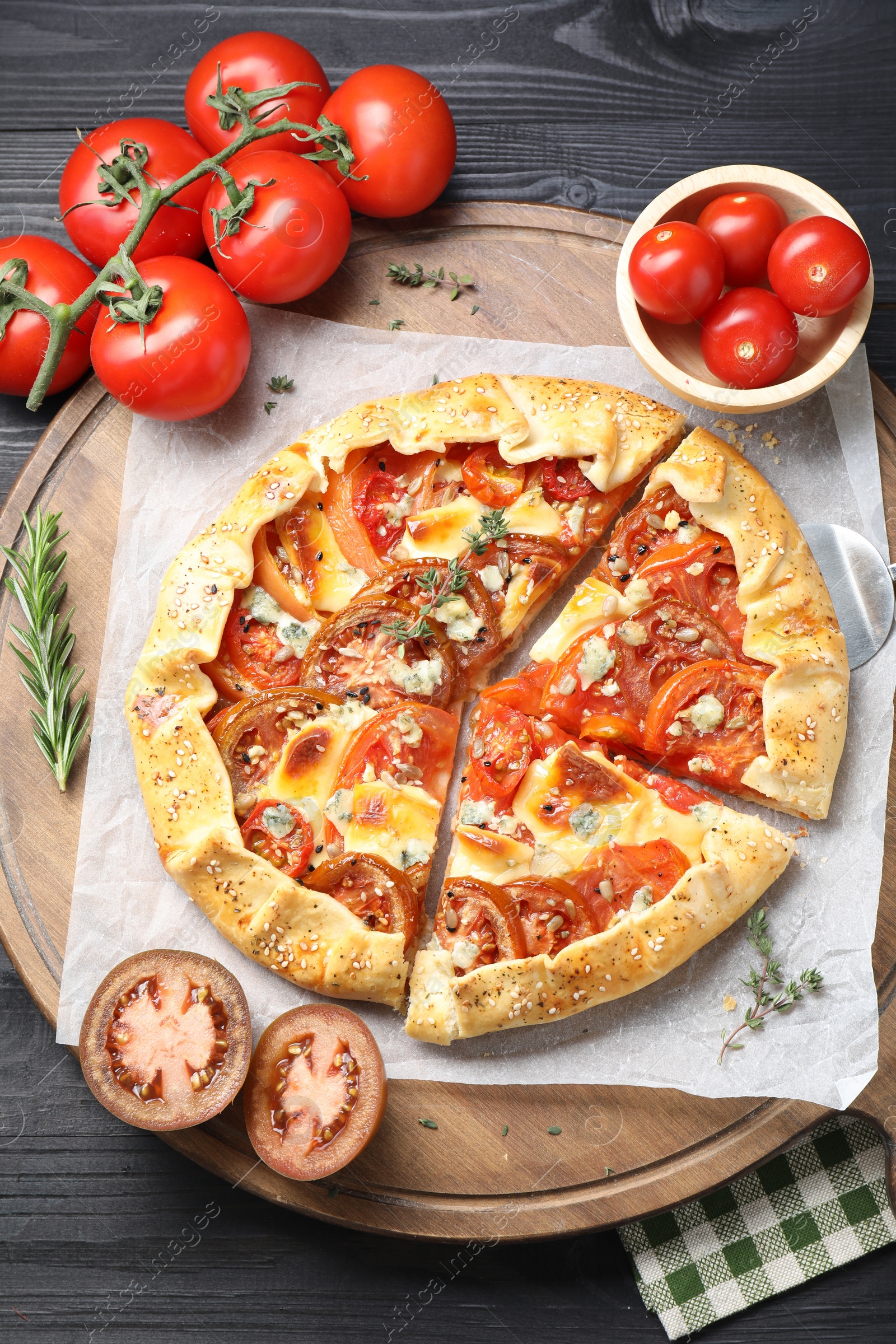 Photo of Tasty galette with tomato and cheese (Caprese galette) on black wooden table, top view