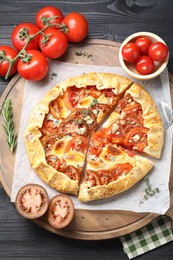 Tasty galette with tomato and cheese (Caprese galette) on black wooden table, top view