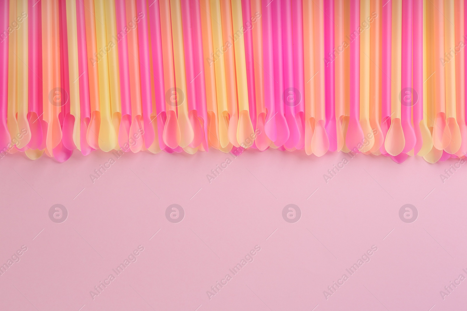 Photo of Heap of colorful plastic drinking straws on pink background, flat lay. Space for text