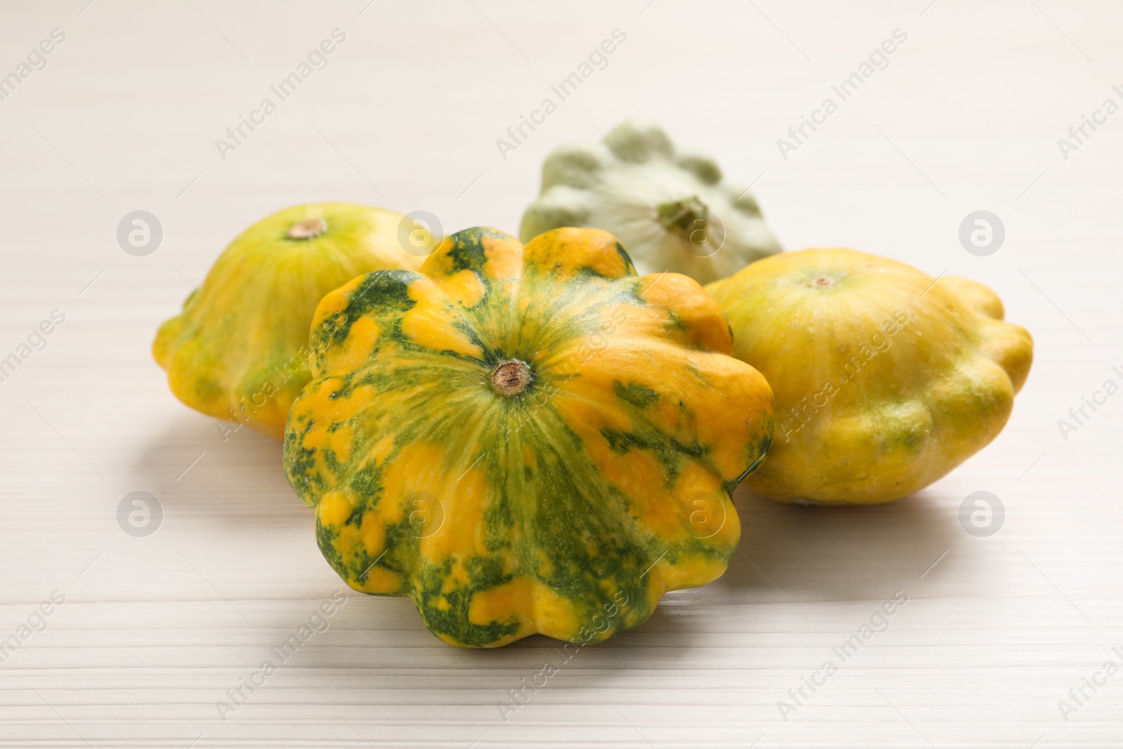 Photo of Fresh ripe pattypan squashes on white wooden table, closeup