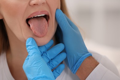 Photo of Doctor examining woman`s oral cavity on blurred background, closeup