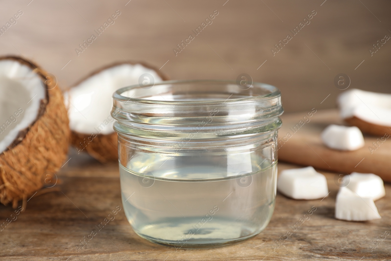 Photo of Coconut oil on wooden table, closeup view