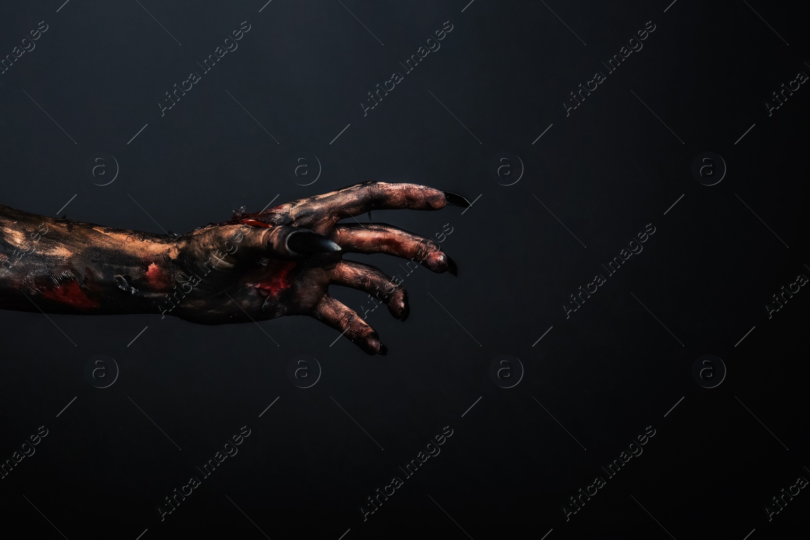 Photo of Scary monster on black background, closeup of hand with space for text. Halloween character