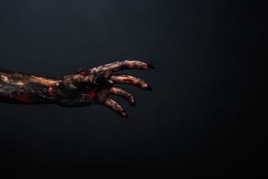 Photo of Scary monster on black background, closeup of hand with space for text. Halloween character