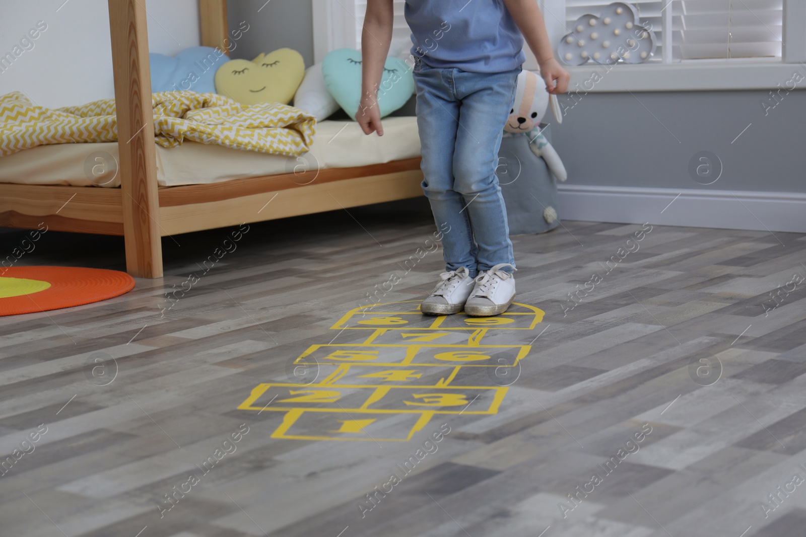 Photo of Little girl playing hopscotch at home, closeup