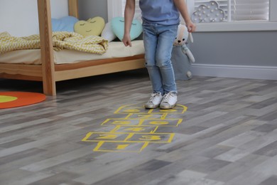 Little girl playing hopscotch at home, closeup