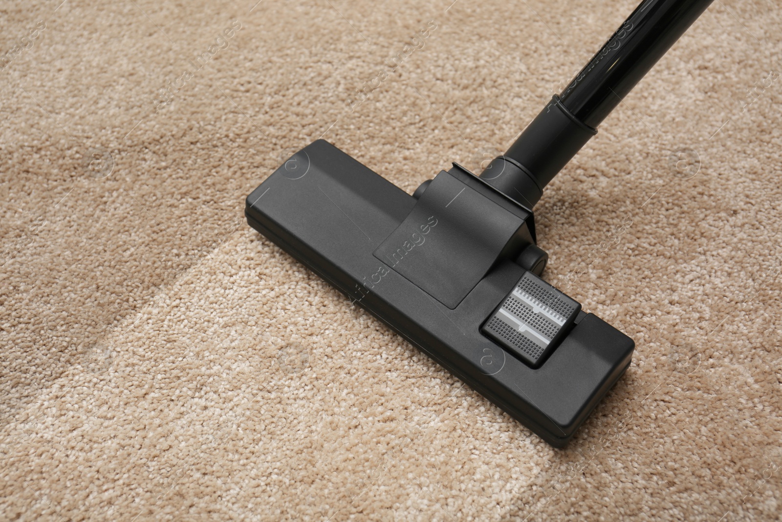 Image of Vacuuming dirty beige carpet. Clean area after using device, closeup