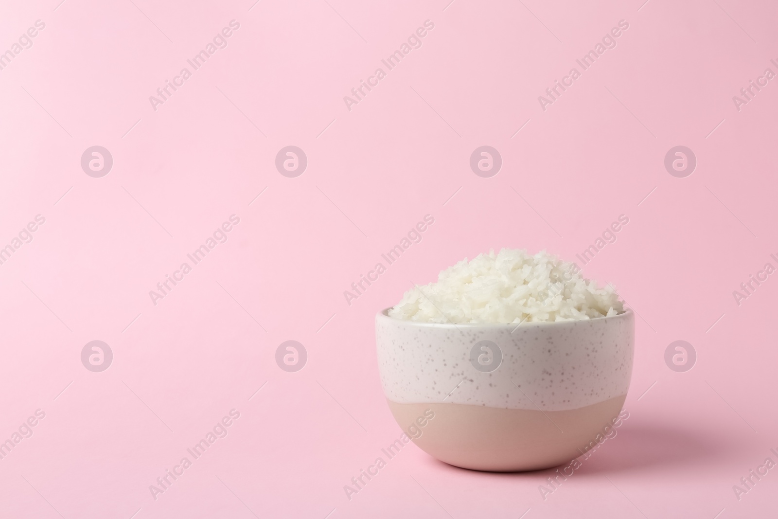 Photo of Bowl of boiled rice on color background. Space for text