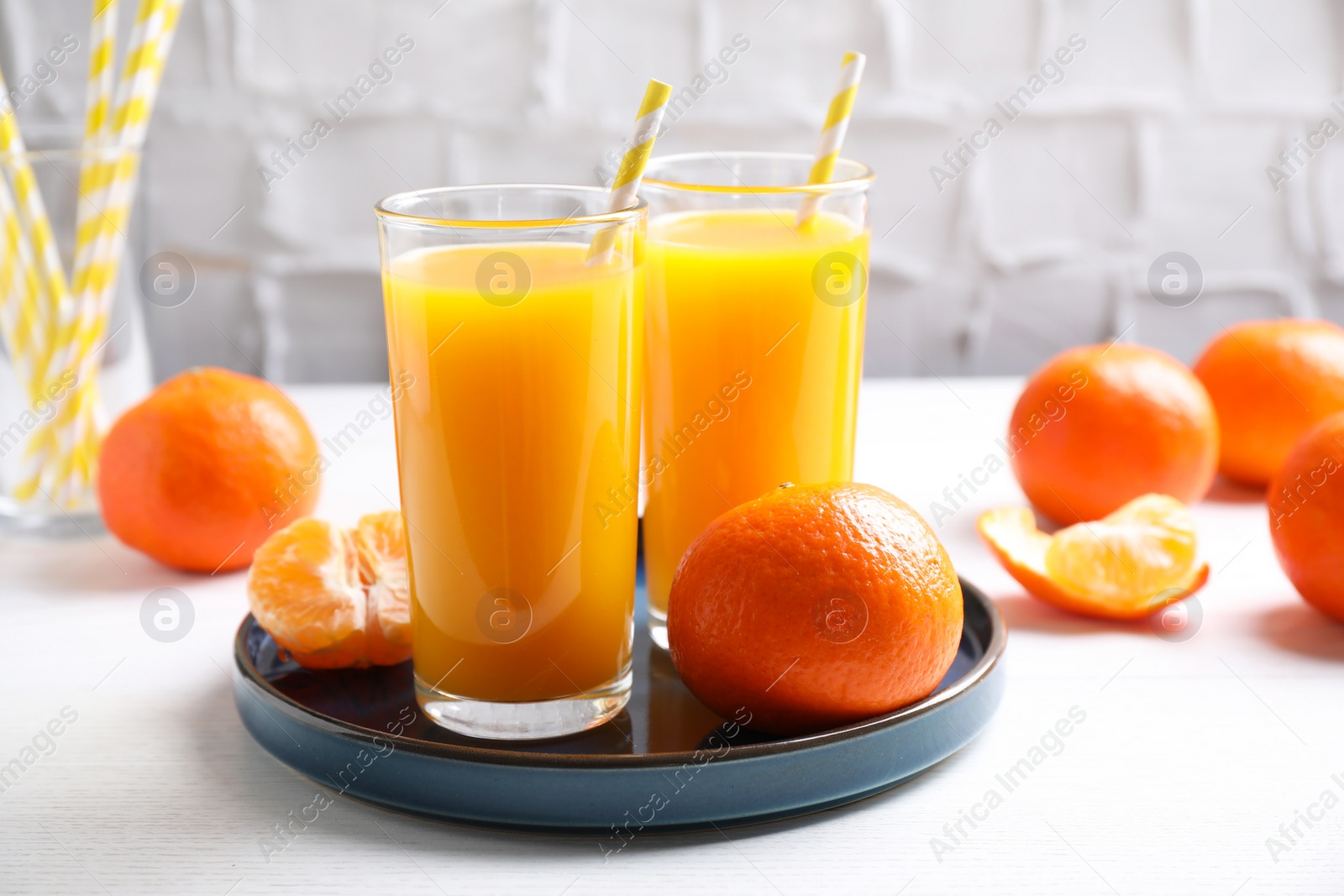 Photo of Glasses of fresh tangerine juice and fruits on white table