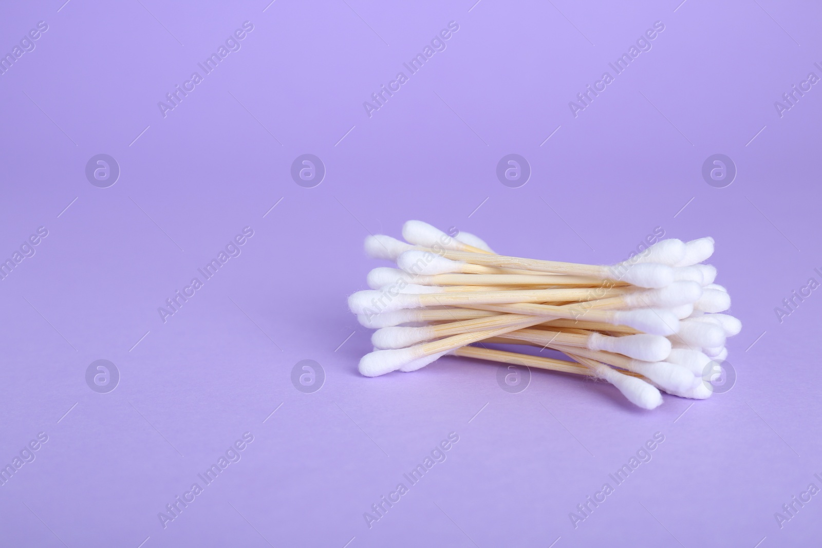 Photo of Wooden cotton buds on violet background. Space for text